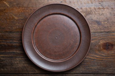 Ahşap arka planda boş bir kil plaka. mesaj için yer. Yukarıdan görünüm