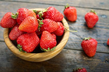 Tahta bir tabakta, ahşap bir arka planda olgun çilekler. tex için yer