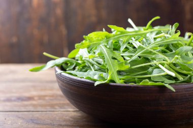 Tahta bir masada, kil tabakta taze yeşil roka salatası. metin için yer