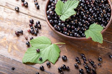 Olgun organik üzümler, kil bir tabakta yeşil yapraklar, ahşap bir zemin üzerinde. Berrie 'nin belirgin dokusu