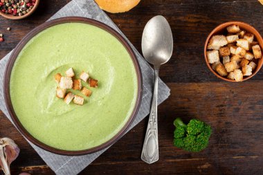 Masadaki tabakta yeşil sebze kremalı brokoli. Yanında taze çörekler ve Borkcol 'ün cilvesi var.