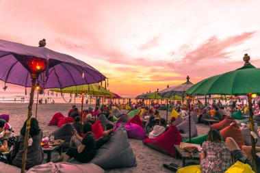 Bali, Endonezya. Ekim 2017 civarı. Gün batımında sahilde eğlenen, içen ve dinlenen bir grup insan.
