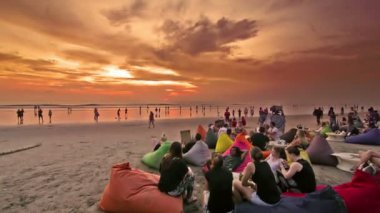 Bali, Endonezya. Ekim 2017 civarı. Gün batımında sahilde eğlenen, içen ve dinlenen bir grup insan.