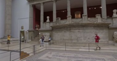 Berlin, Almanya. Mayıs 2018. Pergamon müzesindeki Trajan tapınağını ziyaret eden turistler. Sinematik kamera hareketi.