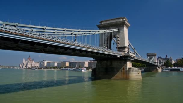Trajekty a chodci v řetězovém mostě v Budapešti, Maďarsko. Maďarský parlament v pozadí