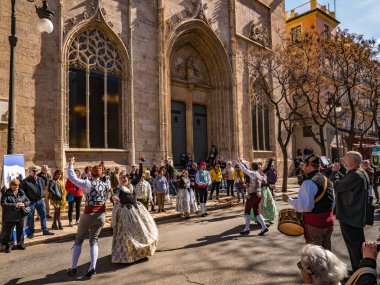 Valencia, İspanya. Mart 2018 civarı. Geleneksel sokak danslarında gösteri yapan bir grup genç. Lonja de la Seda 'nın cephesi, Arkaplanda Meta Borsası Binası.