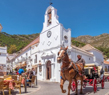 Malaga, İspanya. Mayıs 2018. Mijas sokaklarında turistli bir at arabası, Malaga kıyısındaki bir dağda geleneksel bir beyaz köy. Ba 'da küçük bir kilise ve restoran terasları