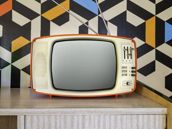 Retro television with vintage wallpaper in the background. Interior decoration from the 70s