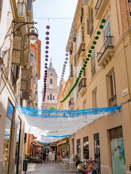 Málaga, España. Alrededor de agosto 2018. Una de las calles decoradas de Málaga durante el festival de la feria y la catedral al fondo . — Foto de Stock