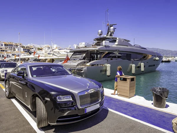 Malaga, İspanya, Ağustos 2018. Puerto Banus 'ta büyük bir yatın yanında Rolls-Royce marka bir araba. Marbella' da jet sosyetesiyle ünlü lüks bir liman ve marina.
