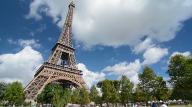 Güneşli bir günde Eiffel kulesinin yanındaki parkta dinlenen turistler,