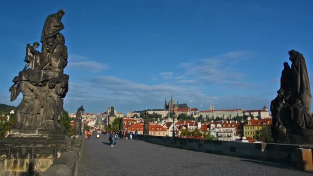 Touristen besuchen an einem sonnigen Tag die Karlsbrücke. Prager Burg und Veitsdom im Hintergrund. — Stockvideo