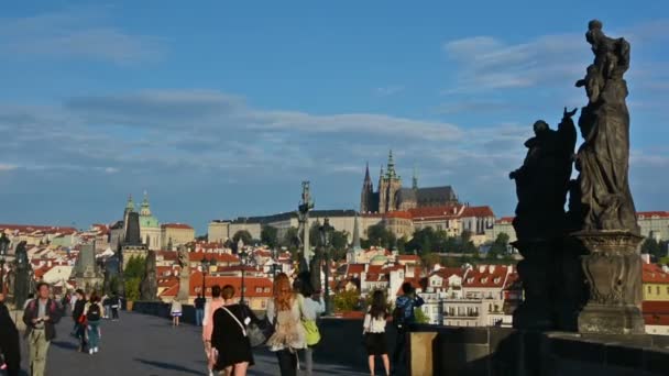 Turistická návštěva Karlova mostu za slunečného dne. Pražský hrad a katedrála sv. Víta na pozadí. — Stock video