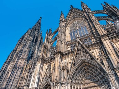 Güneşli bir günde Almanya 'nın Köln kentindeki Gotik Aziz Peter Katedrali. Kulelerin, kemerlerin ve pencerelerin detaylarıyla güzel bir şehir manzarası