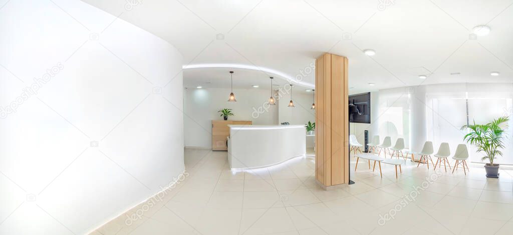 Panorama of a bright reception and waiting room in a clinic with desk, modern chairs and plants. Indoor mockup with screen with copy space.