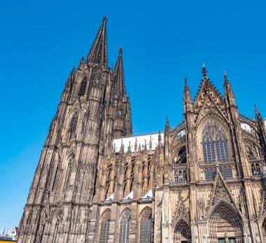 Güneşli bir günde Almanya 'nın Köln kentindeki Gotik Aziz Peter Katedrali. Kulelerin, kemerlerin ve pencerelerin detaylarıyla güzel bir şehir manzarası