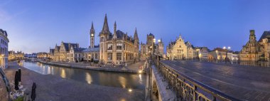 Graslei 'nin panoramik manzarası, Gent, Belçika' daki Lys Nehri 'nin yanındaki rıhtımda rıhtımda ve alacakaranlıkta St. Michael Köprüsü' nde. Gent eski kasabası güzel aydınlatılmış binaları ve simgeleri ile ünlüdür. 