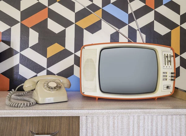 Retro television with vintage telephone and wallpaper in the background. Template interior decoration with ceramic decoration from the 70s