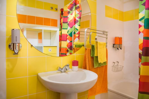 Nowoczesna i kolorowa łazienka. Żółte i pomarańczowe ręczniki i płytki. — Zdjęcie stockowe