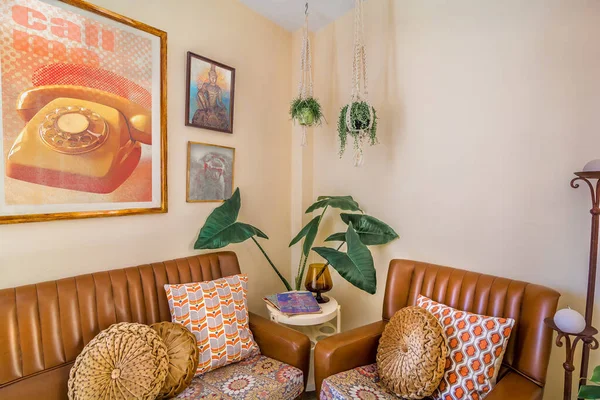 Vintage interior decoration with a retro sofa, magazines,old movies posters,  macrame plant hangers, retro print cushions.