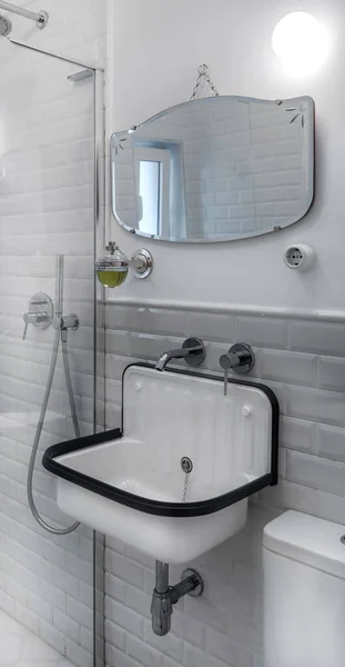 Zabytkowe wnętrze łazienki ze stali i klasycznych płytek. Oryginalny zlewozmywak z białego lakierowanego metalu i czarnej gumy. Antyczne lustro. — Zdjęcie stockowe