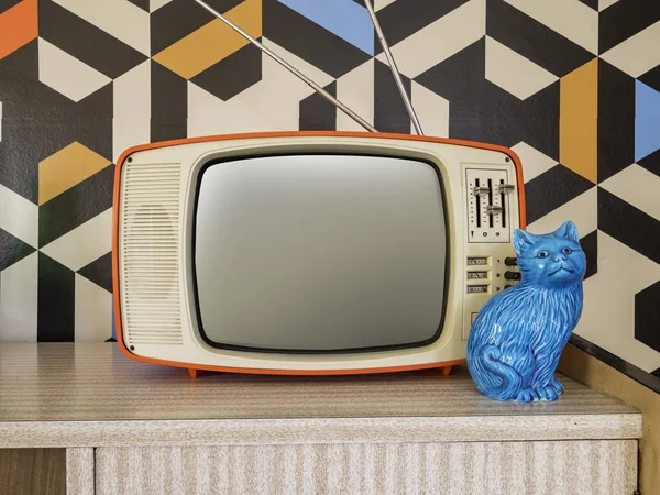 Arka planda antika duvar kağıdı olan eski bir televizyon. 70 'lerden kalma iç dekorasyon seramik figürü.