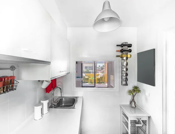 Moderna decoración interior de una cocina luminosa con mostrador blanco y armarios, lavadora, microondas, fregadero, bandeja y accesorios en rojo — Foto de Stock
