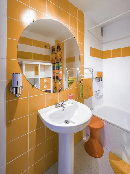 Nowoczesna i kolorowa łazienka. Wystrój wnętrz z pomarańczowymi ręcznikami i płytkami oraz zabytkowymi meblami z lat 70. — Zdjęcie stockowe