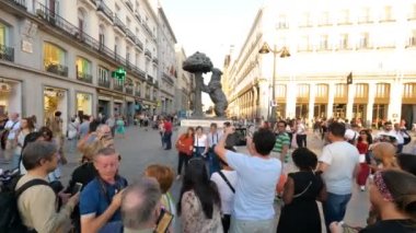Madrid, İspanya. Kasım 2018. Günbatımında Puerta del Sol Meydanı 'nda bulunan ayı heykeli ve çilek ağacıyla resim çeken turist.