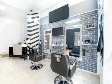 Modern, parlak güzellik salonu. Kuaför salonu iç işleri ve endüstriyel görünümü çok az. Aynalı, sandalyeli, TV ekranlı ve sahte pankartlı siyah beyaz dekorasyon