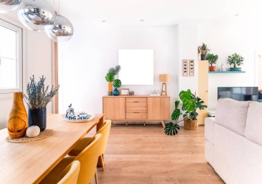 Doğal stili, ahşap masası, seramikleri, resimleri, kitapları ve bitkileri olan rahat, şık, parlak bir oturma odası. Geniş modern salon. Toprak renkleri ile iç mekan..