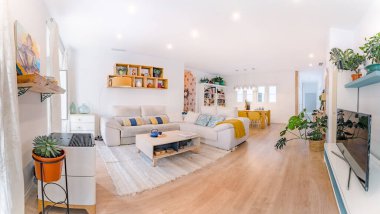Doğal stili, kanepesi, ahşap masası, resimleri, kitapları ve bitkileri olan rahat, şık bir oturma odası. Geniş modern salon. Toprak renkleri ile iç mekan..