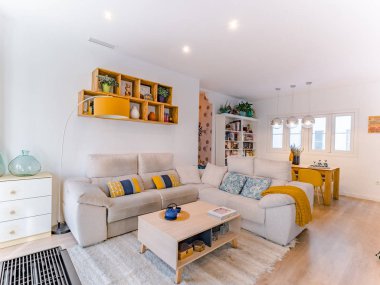 Malaga, İspanya. Ekim 2019 civarı. Doğal stili, kanepesi, ahşap masası, resimleri, kitapları ve bitkileri olan rahat, şık bir oturma odası. Geniş modern salon. Toprak renkleri ile iç mekan..
