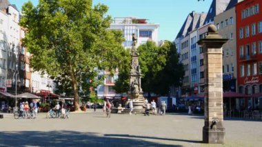 Köln, Almanya. Kasım 2019 civarı. Bisikletli turistler, Alter Markt 'ın merkezinde Jan von Werth' ün heykeliyle çeşmeyi ziyaret ediyorlar. Ekoloji ve bisiklet turizmi kavramı.