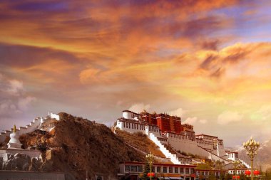 Tibet, Lhasa 'daki Potala Sarayı' nın yan manzarası dramatik bulutlarla kaplı renkli bir günbatımı gökyüzüne karşı..