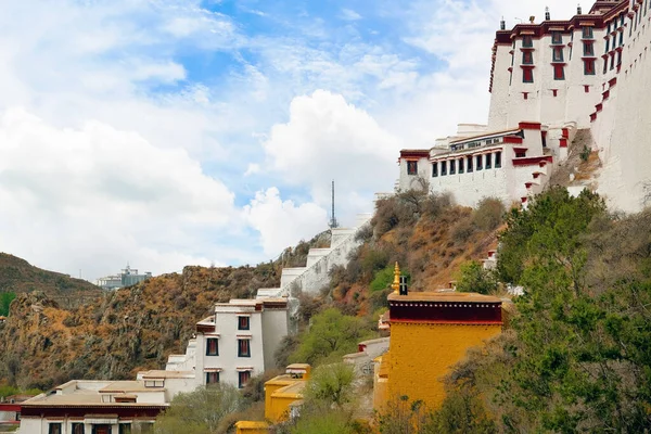 Oldalnézetben a Potala palota Lhászában, Tibetben, zöld növényzettel körülvéve, a kék nyári égbolton fehér felhők borítják. — Stock Fotó
