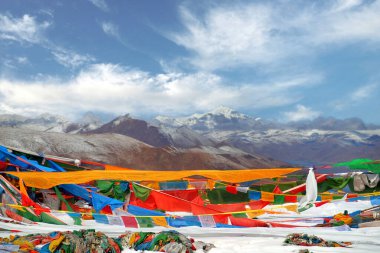 Yamdrok Gölü önünde dua eden Tibet bayrakları, Dağ 'ın kahverengi renklerini yansıtıyor. Naiqinkangsang açık mavi gökyüzüne karşı.