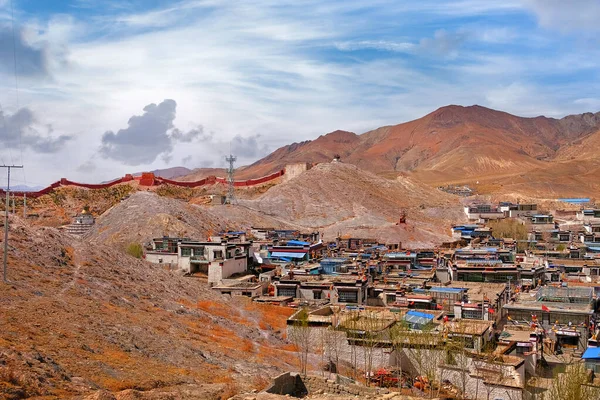 Vista del tradicional pueblo tibetano rodeado por las montañas del Himalaya, contra un cielo azul cubierto de nubes blancas . — Foto de Stock