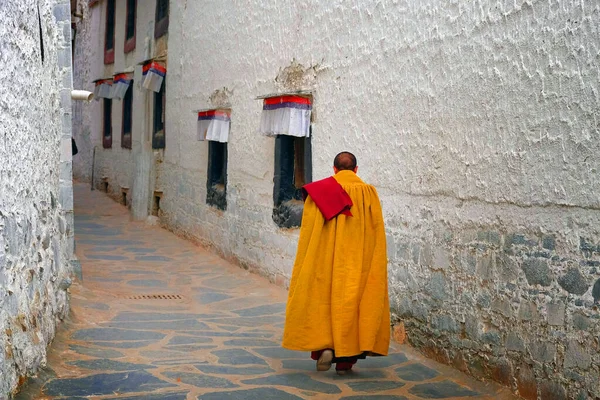 Monje tibetano, vestido de amarillo, caminando por las calles del Monasterio de Tashilhunpo, en Shigatse . — Foto de Stock