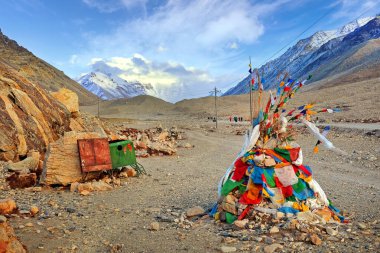 Rongpu Manastırı yakınlarında renkli dua eden bayraklarla kaplı taş oluşumunun görüntüsü Everest Dağı 'nın üzerindeki mavi gökyüzüne karşı..