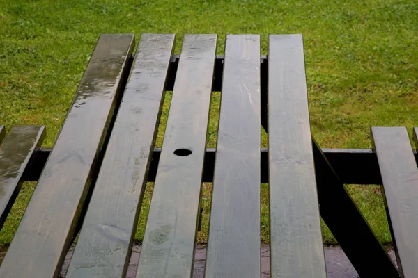Дождь на скамейке для пикника в парке — стоковое фото