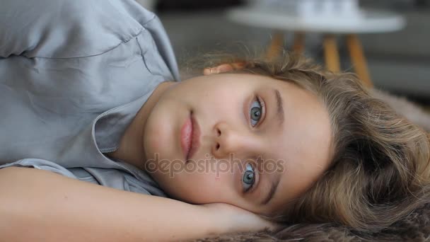 Дитина засинає, розбухає, заплющує очі. Дивовижно красива блакитноока дівчина дивиться на камеру . — стокове відео