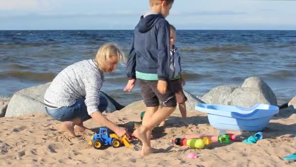 ビーチ 砂で遊んで彼女の息子を持つ若い女性の家族の休日 海海岸夏にママと子供の残り — ストック動画