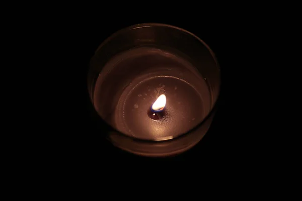 Свеча в стакане на черном фоне — стоковое фото