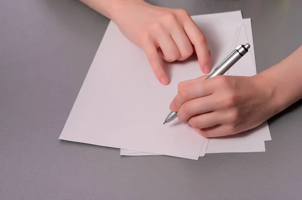 Human hands with pencil writing on paper and erase rubber on wooden table background