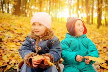 Erkek ve kız kardeşi dışında oynarken sonbahar yaprakları.