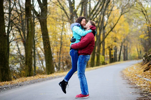 Muž zvedne do náruče své milované, pokud jde v nádherný podzimní den — Stock fotografie