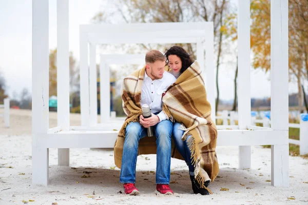 Молода пара обіймається і покрита теплою ковдрою сидить — стокове фото