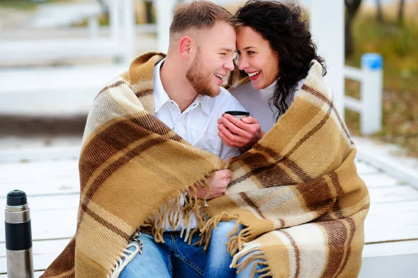 Genç çift kucaklayan ve bir sıcak battaniye oturma o ile kaplı — Stok fotoğraf