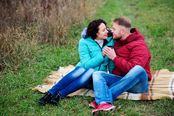 Jeune couple assis sur le plaid et boire du café d'un thermo — Photo